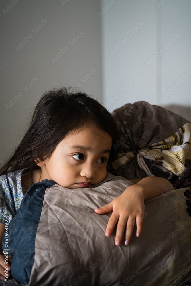 Close up toddler asian girl lying in bed with woke up looks. Comfy mattress, soft pillow, fresh bedding, healthy enough sleeping, nap time concept Close up toddler asian girl lying in bed with woke up looks. Comfy mattress, soft pillow, fresh bedding, healthy enough sleeping, nap time concept