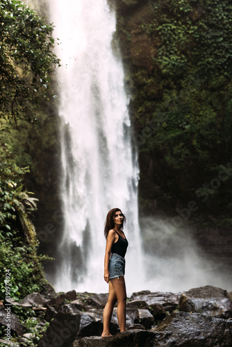 Beautiful girl at a waterfall on the island of Bali Indonesia. Sexy woman at the waterfall. Beautiful woman posing at a waterfall. Copy space
