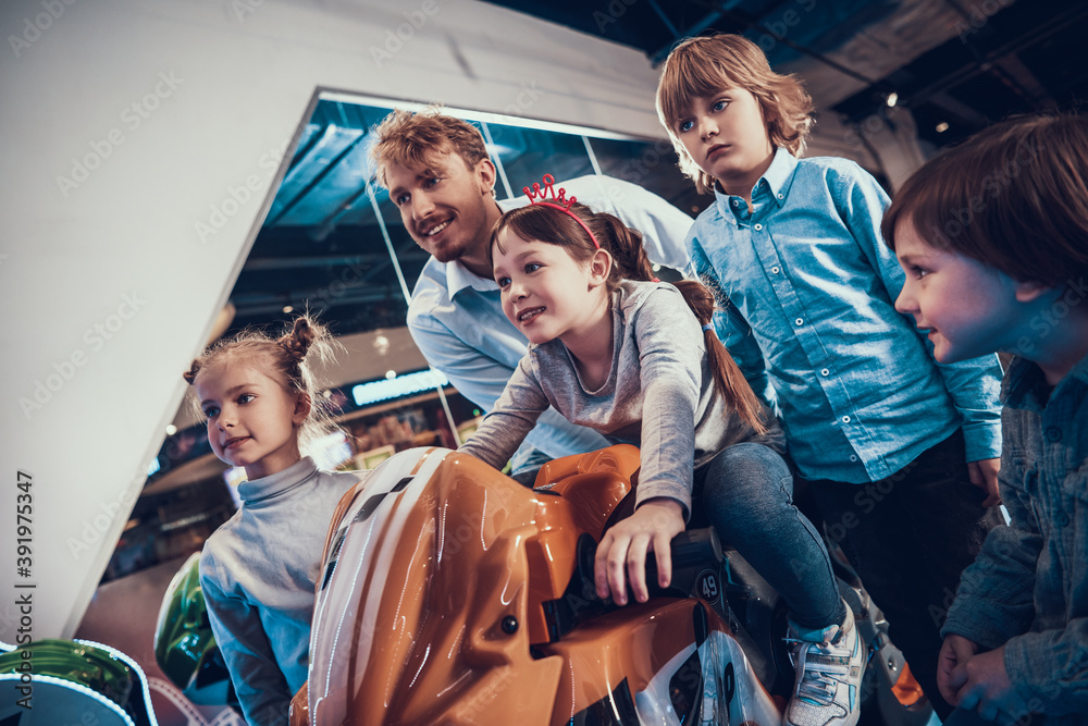 Obraz premium Dad and children watch as girl drives motorcycle.