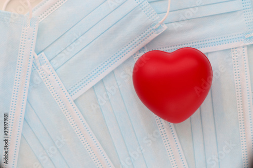 Quadro su tela Red toy heart lying on table among medical protective masks in clinic