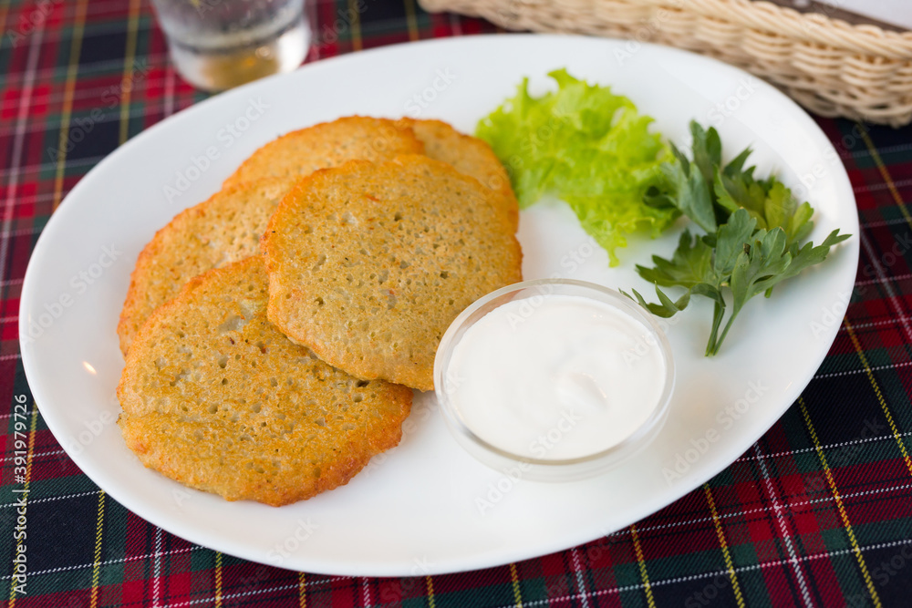 potato pancakes with sour cream and herbs on white plate potato pancakes with sour cream and herbs on white plate