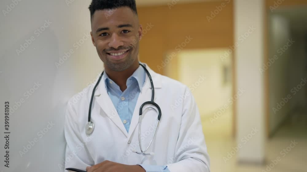 Portrait of smiling doctor sitting at desk, looking at camera