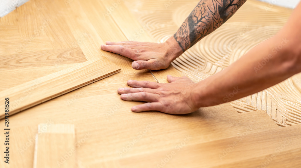 Detailaufnahme wie ein junger Handwerker einen Eichen Fischgrät Boden verlegt Detailaufnahme wie ein junger Handwerker einen Eichen Fischgrät Boden verlegt