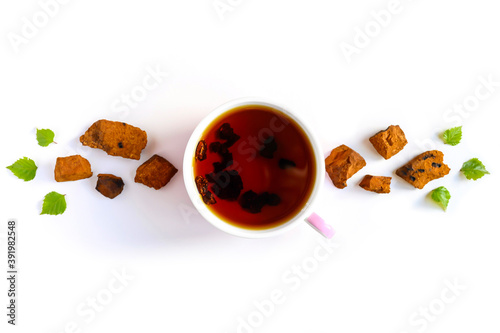 Cup of tea of birch chaga mushroom and crushed chaga fungus pieces for tea brewing isolated on a white background photo