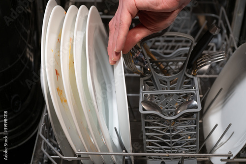 Places the dishes in the dishwasher.