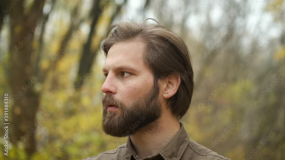 A brutal bearded Caucasian man standing in an autumn park looking at the camera and straightening his hair. Self-isolation during an epidemic A brutal bearded Caucasian man standing in an autumn park looking at the camera and straightening his hair. Self-isolation during an epidemic