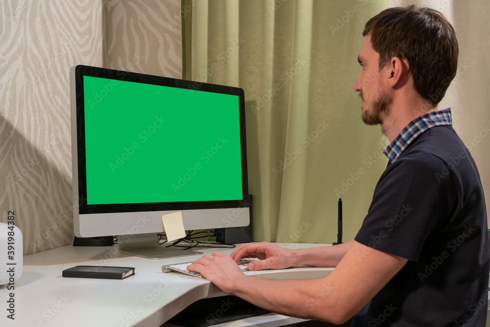 A man works in front of a computer with a green screen. A man works in front of a computer with a green screen.