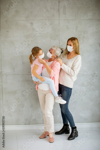 Senior woman, adult woman and little girl, three generations with protective facial masks at home © BGStock72