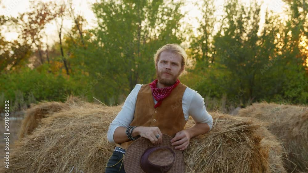 Handsome cowboy posing near hay on his farm Handsome cowboy posing near hay on his farm