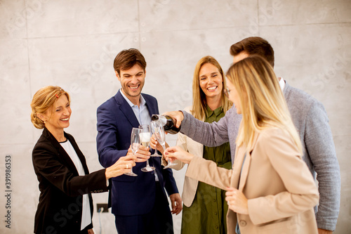 Group of business people celebrating and toasting with champagne in the office