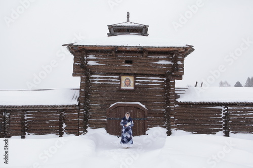 Russian girl, snowy winter. Сossack jail in Semiluzhniki village, Tomsk oblast. Russian folk style in architecture. Tomsk region landmark, monument. Snowfall photo