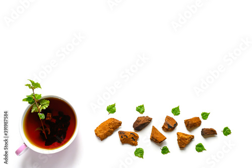 Cup of tea of birch chaga mushroom and crushed chaga fungus pieces for tea brewing isolated on a white background. space for text photo