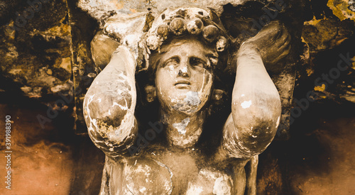 Bild auf Leinwand Ancient dirty stone statue of Sisyphus rolling very big stone to top of high mountain rock in the kingdom of Hades, which beforу reach the top of mountain rolled back down every time