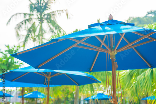 Beautiful empty chair with umbrella around outdoor swimming pool