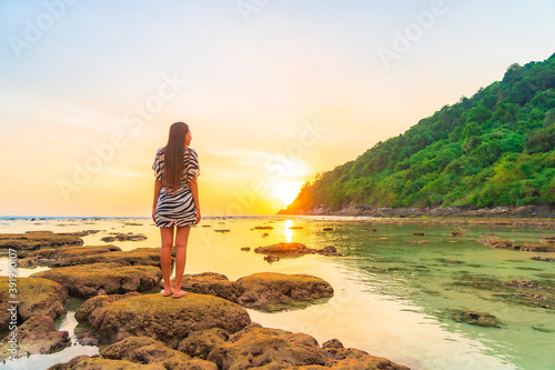 Portrait asian woman stand on the rock at sunset around beach sea ocean