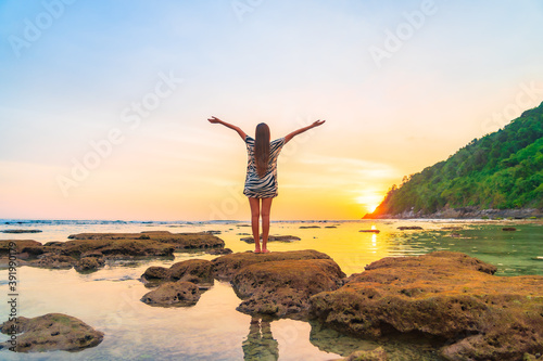 Portrait asian woman stand on the rock at sunset around beach sea ocean
