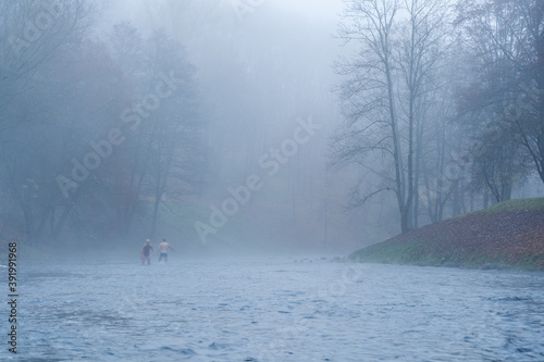Man and woman bathing in cold water river in November at 0 degrees, misty foggy morning in Vilnius, Lithuania