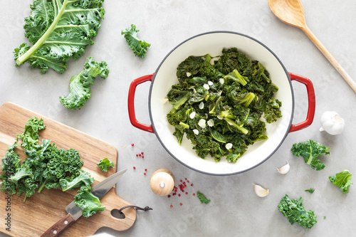 Sauteed kale with garlic in cast iron pan on kitchen table, healthy food concept, superfood