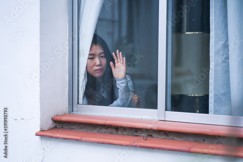 girl in stress at home - dramatic portrait of young sad and depressed Asian Korean woman on window feeling worried and desperate during covid19 stay home and lockdown