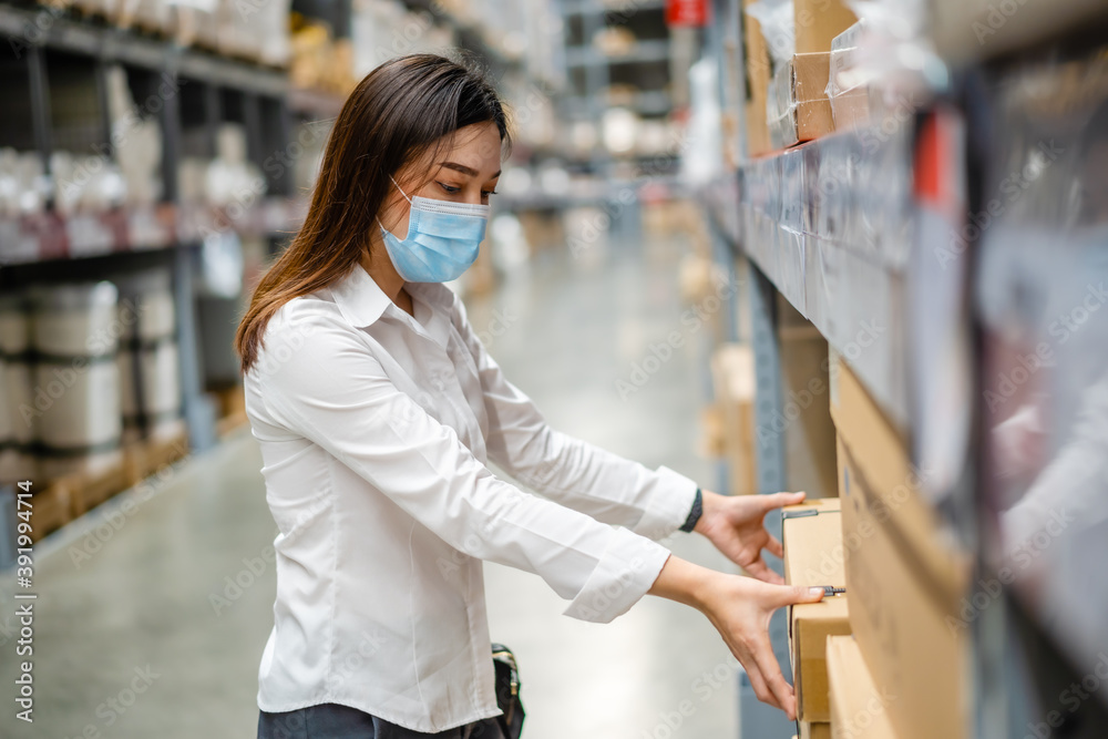 woman with medical mask looking and shopping in warehouse store during coronavirus (covid-19) pandemic.