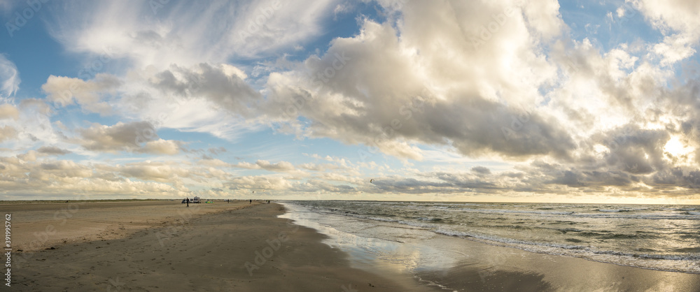 Beach sand with blue sky and dramatic clouds at coastline waterfront in soft evening sunset light. Romo Bilstrand, Lakolk Strand, North Sea, Denmark. Beach sand with blue sky and dramatic clouds at coastline waterfront in soft evening sunset light. Romo Bilstrand, Lakolk Strand, North Sea, Denmark.