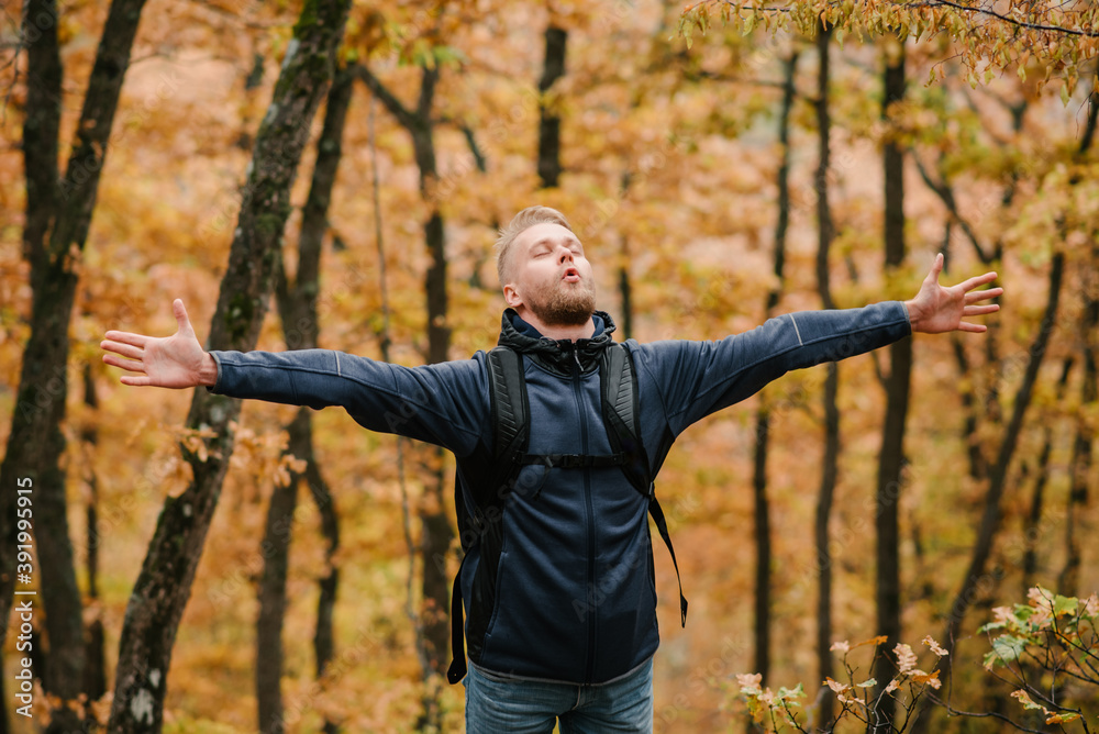 A man traveler in the autumn forest raised his hands. A man traveler in the autumn forest raised his hands.