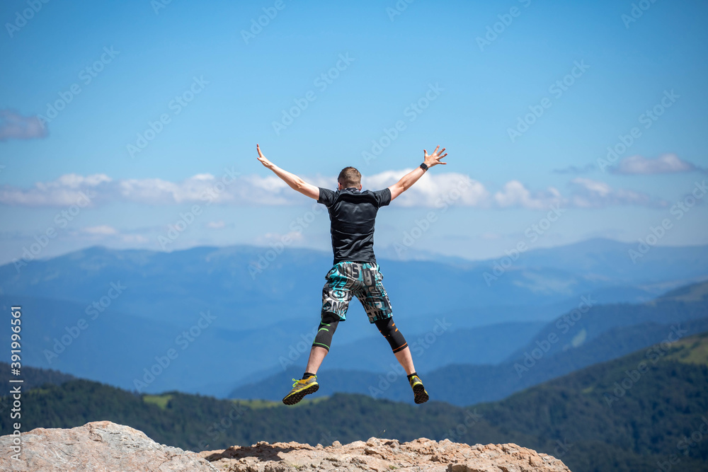 Young man jumping for joy on the top of the mountain Young man jumping for joy on the top of the mountain