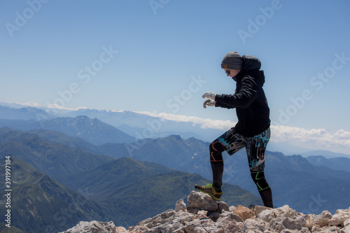 Young man at the top of the mountain admires the panorama of the mountains