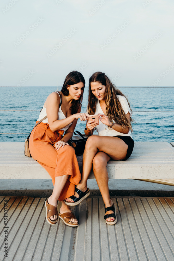 two women talk and you look at a mobile phone animatedly