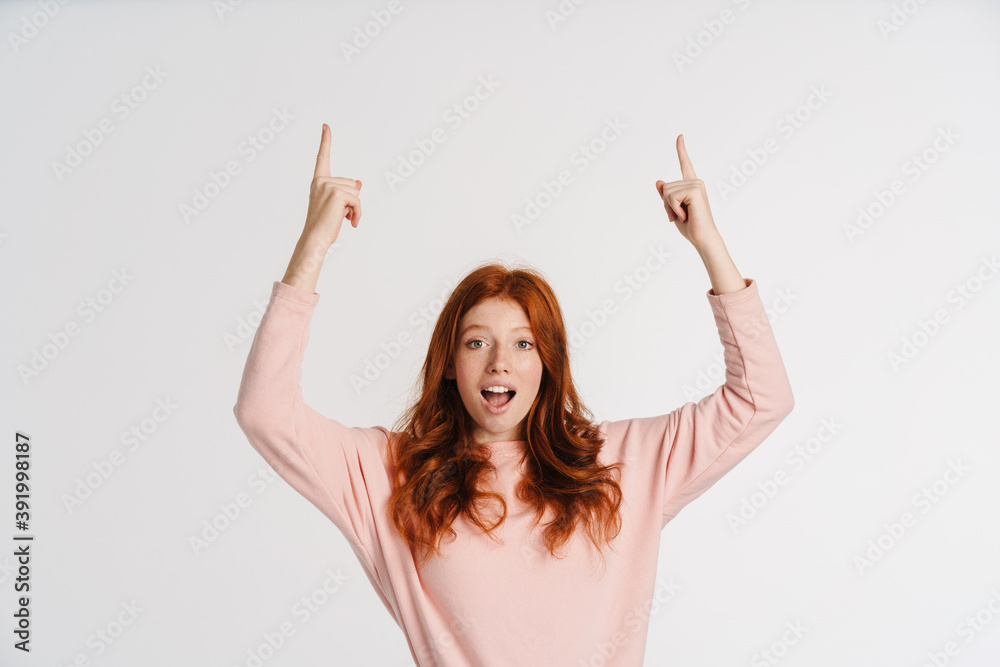 Ginger beautiful excited girl smiling and pointing fingers upward Ginger beautiful excited girl smiling and pointing fingers upward