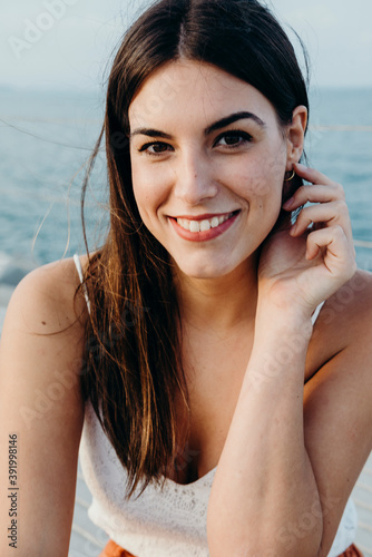 brunette woman poses for a natural portrait with the sea in the background