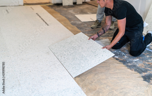 ein fleißiger Bodenleger verlegt spezielle Platten, um einen Höhenunterschied in einer Altbauwohnung auszugleichen, um anschließend darauf Parkett zu verlegen photo