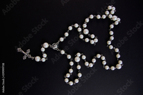 White rosary on black background, view from above