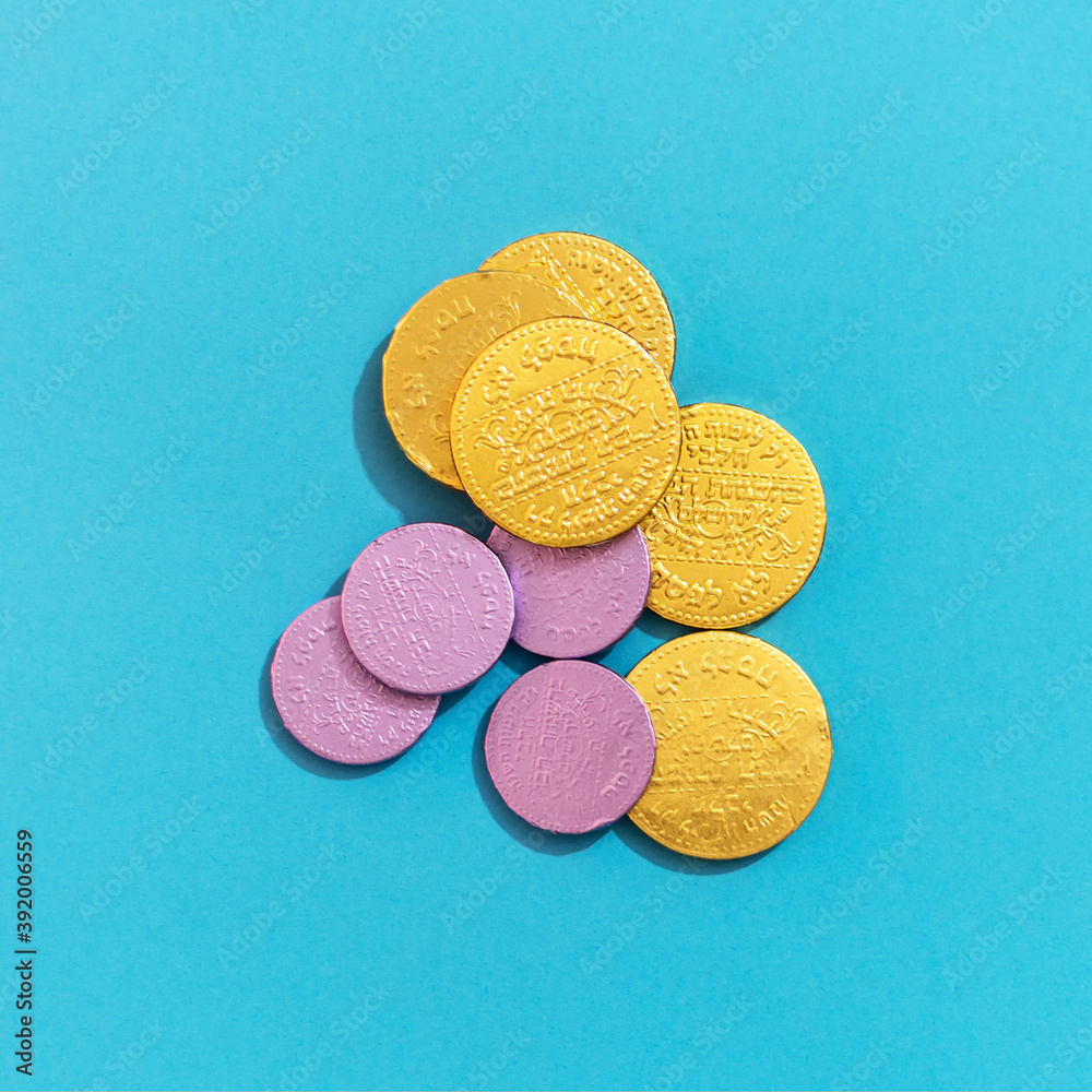Close up of Hanukkah gelt (money) or chocolate coins, top view on light blue background. Close up of Hanukkah gelt (money) or chocolate coins, top view on light blue background.