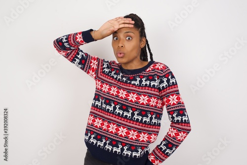 Young beautiful African American woman wearing Christmas sweater wiping forehead with hand making phew gesture, expressing relief feels happy that he prevented huge disaster. It was close enough photo