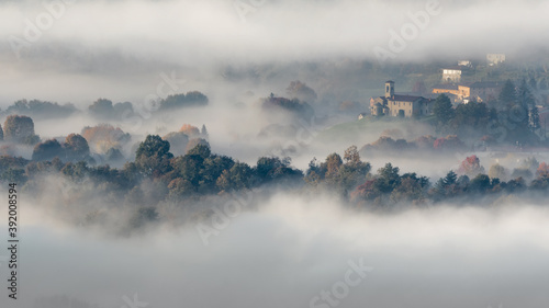 Italian town wrapped by mist at dawn  Lombardy