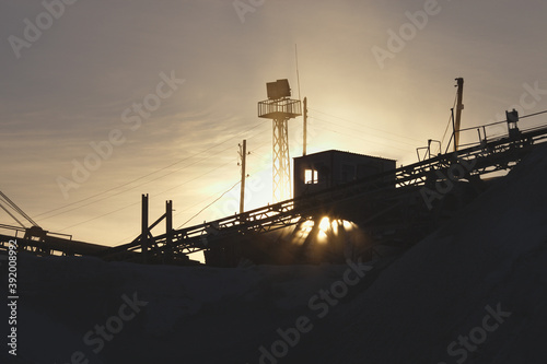 Fragment constructions of stone crushing equipment at the ore-dressing plant in the rays of the setting sun, close-up. Industrial landscape.