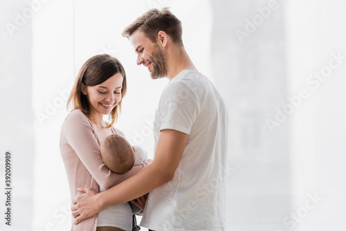 caring woman holding in arms infant boy near cheerful husband