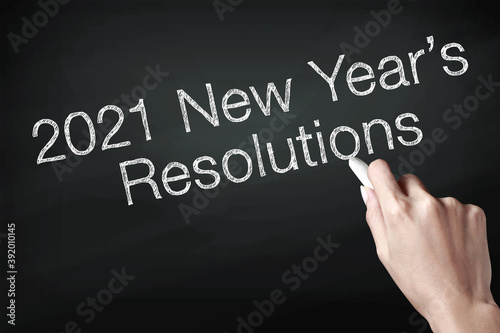 Hand holding a chalk and writing 2021 new year resolutions
