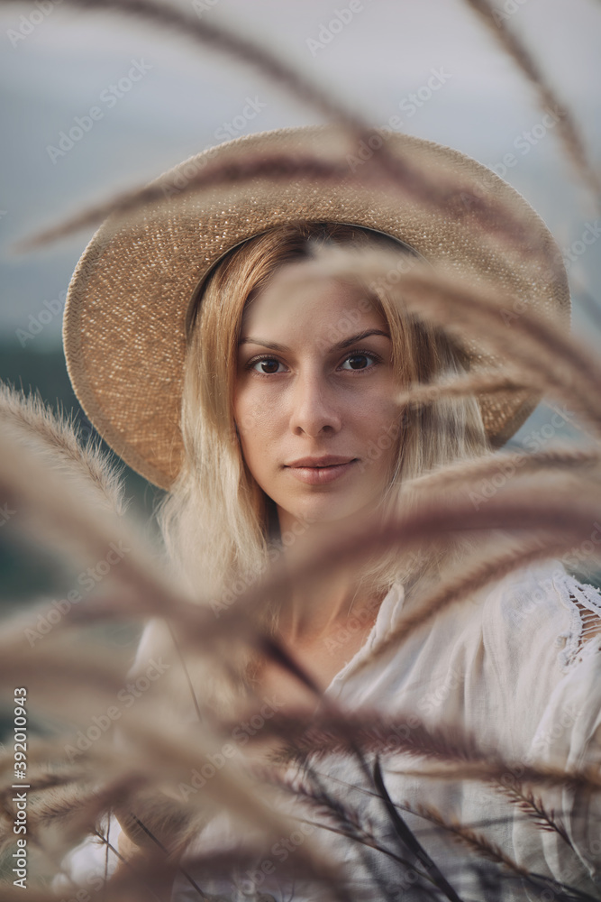 The blonde in a linen dress walks among herbs and wildflowers on a meadow in the mountains. A woman in the Boho style, resting in the countryside, a simple village lifestyle