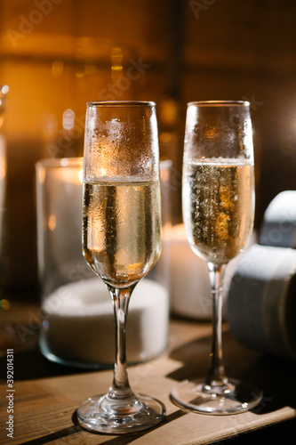 Glasses with champagne on the table. Candles on background
