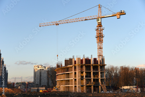 Tower cranes working at construction site against blue sky. Crane lifting a concrete bucket. Construction process of the new residential buildings. Transportation blocks and pouring of the cement mix