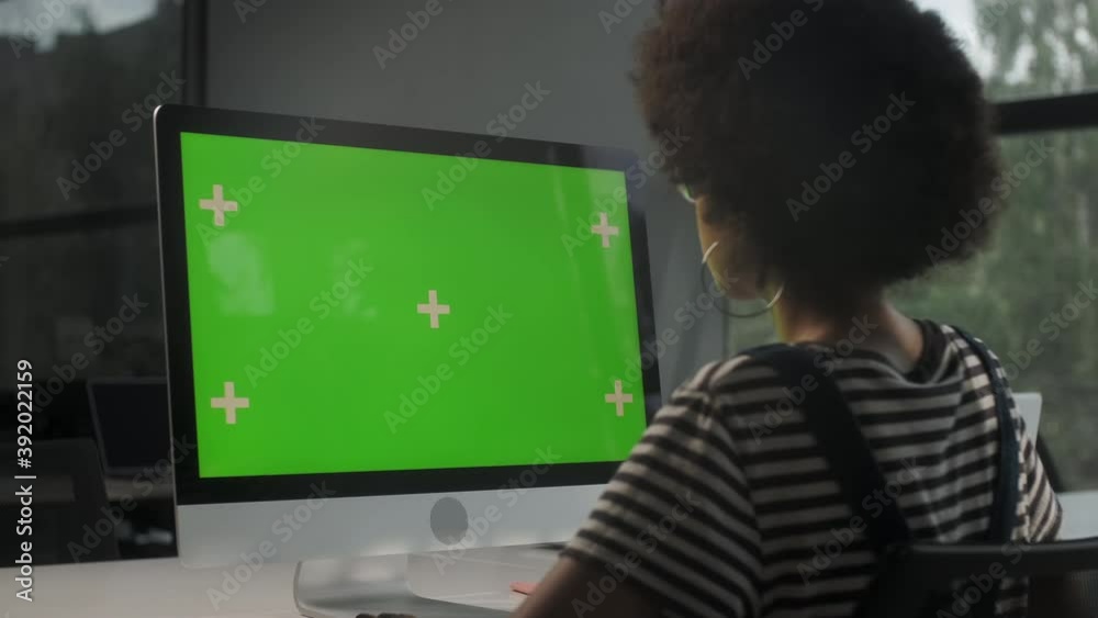 Over The Shoulder Shot Of a Business Woman Working In Office Interior On Pc On Desk, Looking At Display Green Screen. Office Person Using Computer With Computer Green Screen, Sitting at Table.