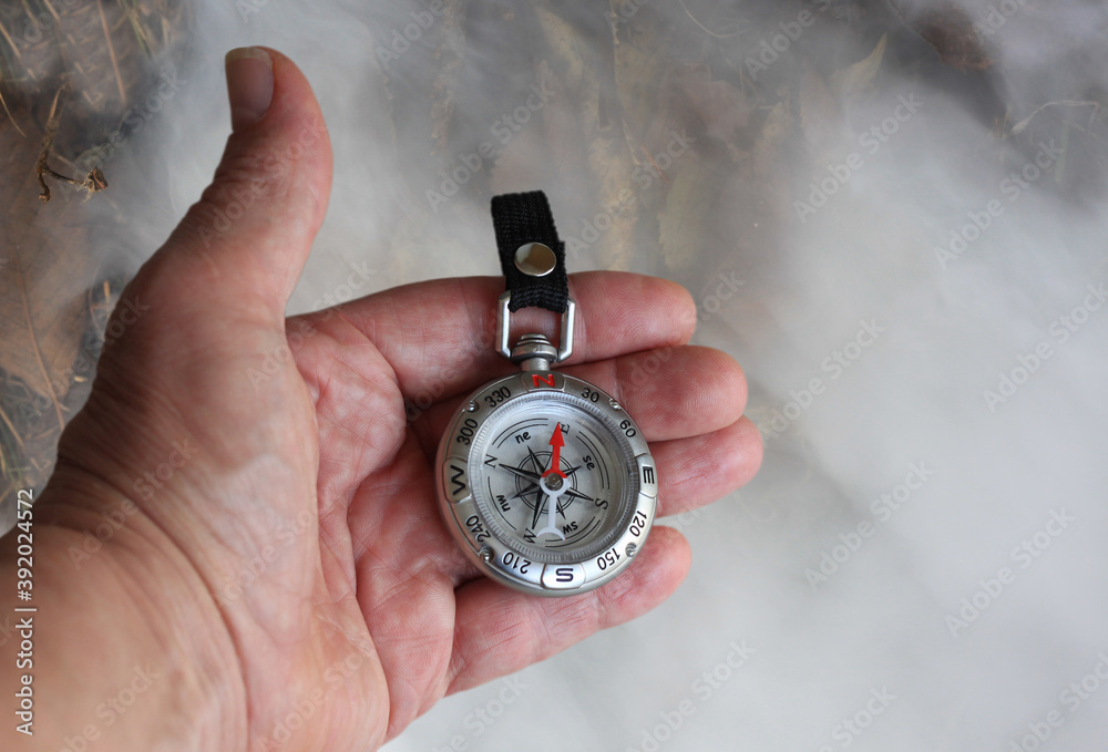 Classic navigation compass in hand on smoke background as symbol of tourism with compass, travel with compass and outdoor activities with compass Classic navigation compass in hand on smoke background as symbol of tourism with compass, travel with compass and outdoor activities with compass