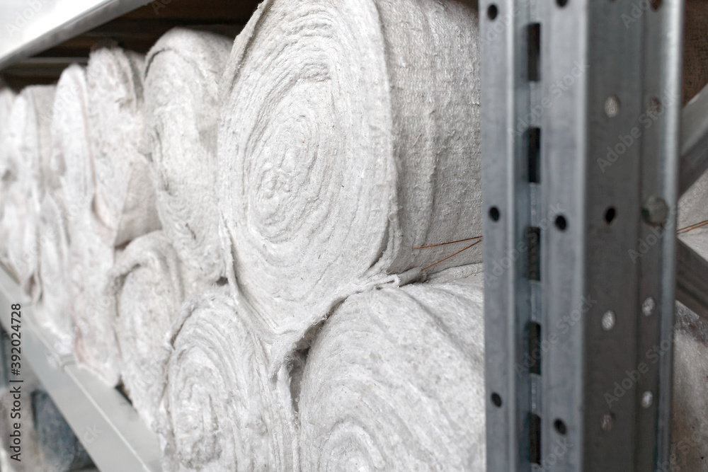 White material in rolls is on the shelves of the warehouse. Covering material. Textiles for the production of rags.