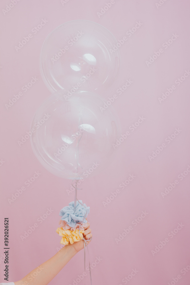 female hand holding balloons. studio photo with pink background.