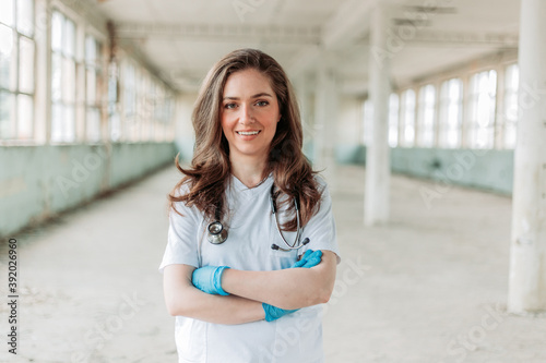 Female doctor smiling. Blurred background. Corona virus fight. Crossed arms Free Download Female doctor smiling. Blurred background. Corona virus fight. Crossed arms - GFXLoad