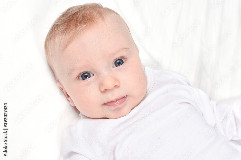 Portrait of Adorable, caucasian baby girl or boy lying on white blanket, looking at camera, on white background. Healthy skin. Baby care concept.