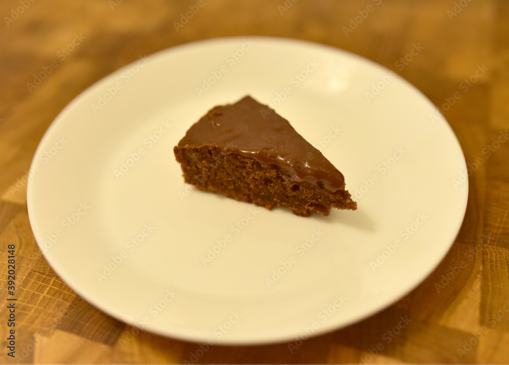 Brown Sugar Chocolate Cake on a white plate on the background of a wooden table in a restaurant. Sweet food concept Brown Sugar Chocolate Cake on a white plate on the background of a wooden table in a restaurant. Sweet food concept