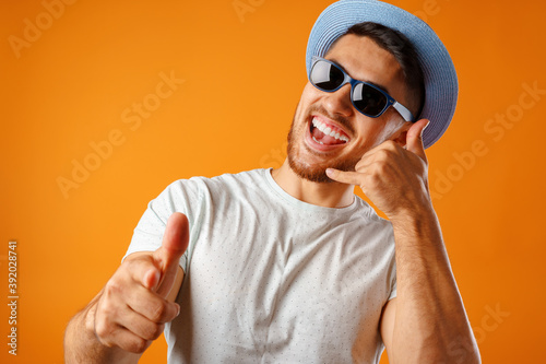 Konstfotografi Overjoyed man in straw hat and sunglasses showing call me gesture